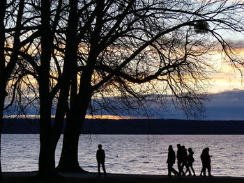 Silhouette people on beach against sky during sunset