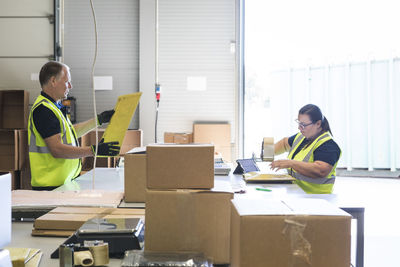 Coworkers packing merchandise on desk at distribution warehouse