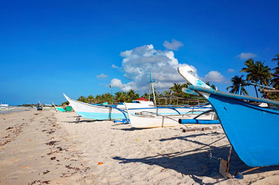 View of beach with boats against blue sky