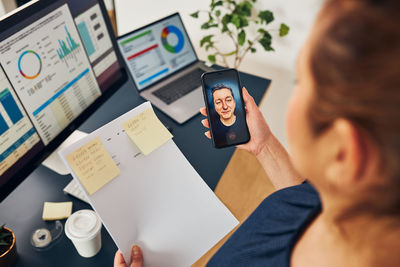 Businesswoman having video call on mobile phone. businesswoman working with data on charts in office