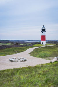 Lighthouse by road amidst buildings against sky