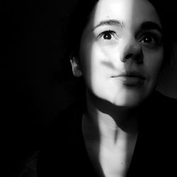 Close-up portrait of young woman against black background