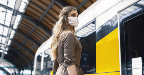 Low angle view of woman wearing mask standing at railroad station