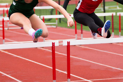 Female athletes hurdling on sports track
