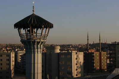 Minaret of mosque in city against clear sky