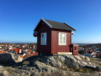 Built structure on rock by building against clear blue sky