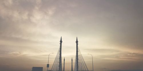 Low angle view of silhouette cranes against sky at sunset