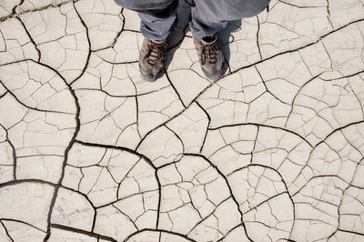 Low section of man standing on dried cracked soil during draught