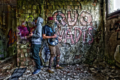 Man standing by graffiti on wall in city