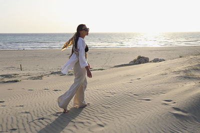 Young woman walking on sand dune at beach, patara, turkiye