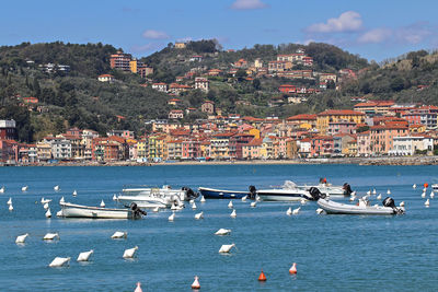 Aerial view of city by sea and buildings against sky