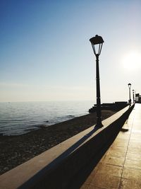 Street light by sea against clear sky