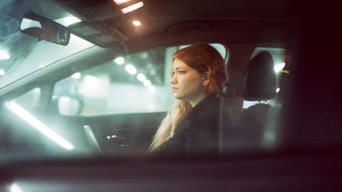 Portrait of young woman looking through car window