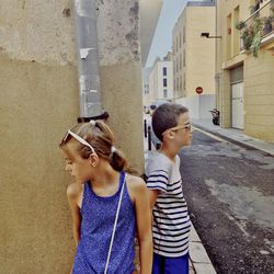 Siblings standing against wall