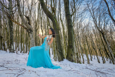 Woman playing on violin in the forest