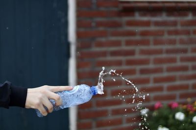 Midsection of person holding umbrella against wall