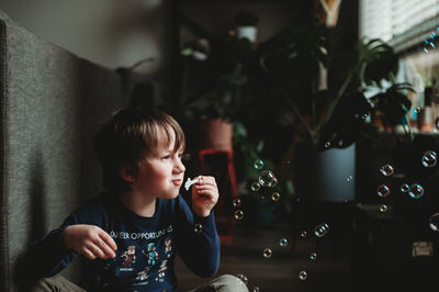 Rear view of boy holding drink at home