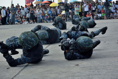 Armed forces performing parade on road with people in background