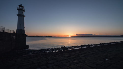 Scenic view of sea by buildings against sky during sunset