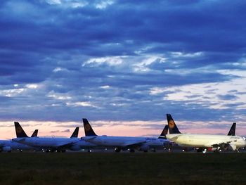 Airplane at airport against sky during sunset