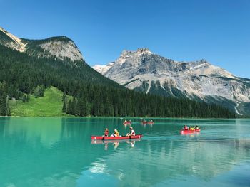 People in boat on lake against mountain range