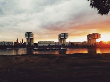 River by buildings against sky at sunset