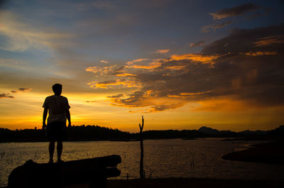 Rear view of silhouette man standing against sky during sunset