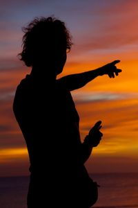 Silhouette woman standing at beach during sunset