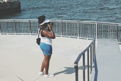 Rear view of man standing on pier over sea