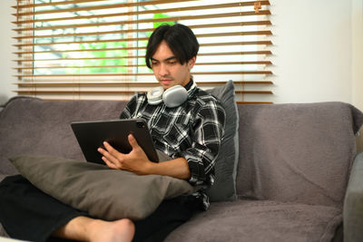 Young woman using laptop while sitting on sofa at home