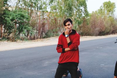 Portrait of young man kneeling on road