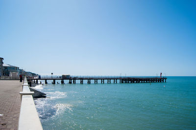 Pier over sea against clear blue sky