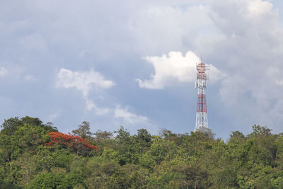 Low angle view of communications tower and trees against sky