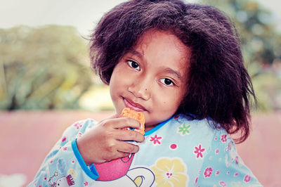 Portrait of girl with messy hair holding toy outdoors