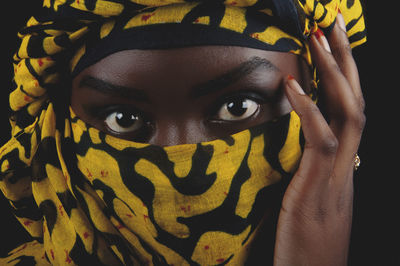 Close-up portrait of woman wearing scarf against black background