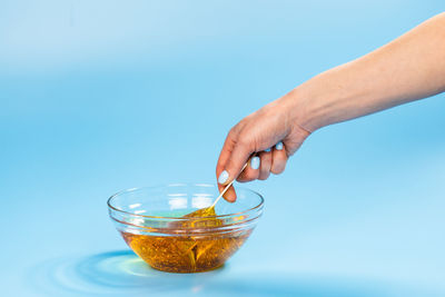 Midsection of woman holding drink against blue background