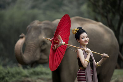 Girl with umbrella sanding in front of elephant