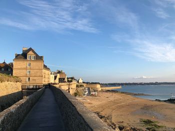 Buildings by sea against sky