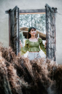 Portrait of woman standing against wall