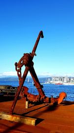 Cranes at harbor against clear blue sky