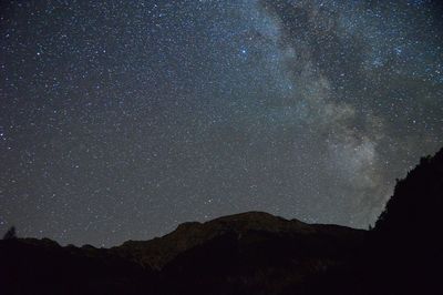 Silhouette mountain against star field at night