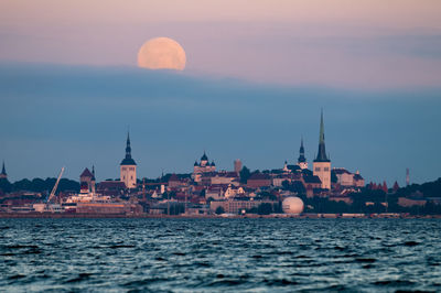 River by city against sky at sunset