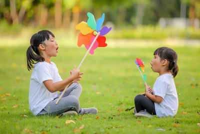 Cute little girl asia playing on the colorful toy windmill in her hands at the lawn.