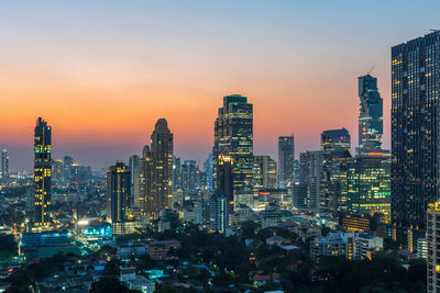 Illuminated buildings in city against sky during sunset