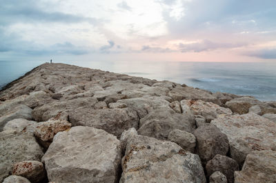 Rocky pier in sea against sky