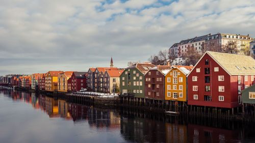 Buildings by river against sky in city