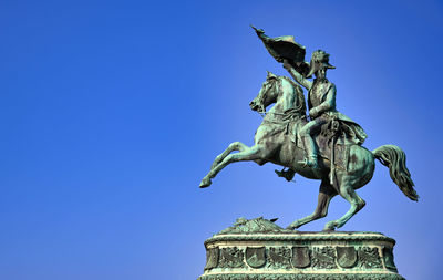 Low angle view of angel statue against clear blue sky