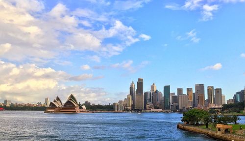 View of city at waterfront against cloudy sky