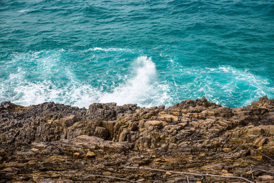 High angle view of waves splashing on rock in sea