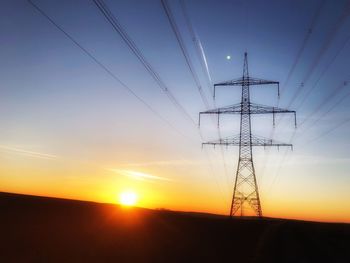 Low angle view of silhouette electricity pylon against sky during sunset